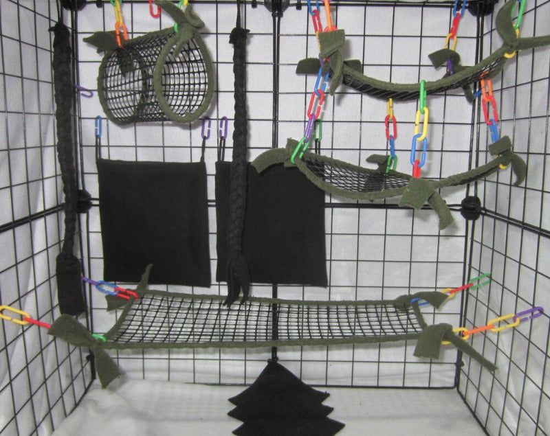 11-piece sugar glider cage set in forest green mesh, featuring breathable hammocks, tunnel, bridge, fleece pouches, braided ropes, and assorted C-links arranged inside a metal cage for small pet comfort and enrichment.
