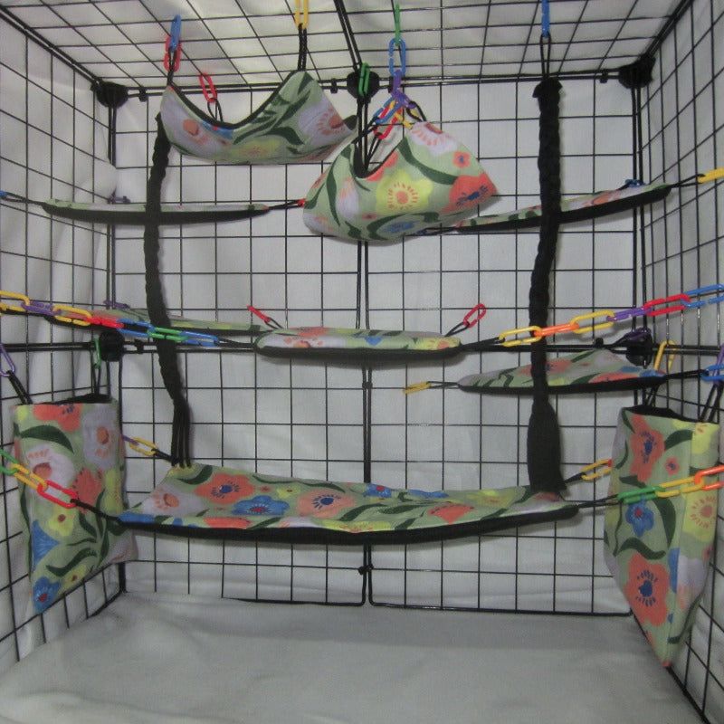 17-piece sugar glider cage set featuring jungle flowers fabric, including hammocks, pouches, and accessories arranged inside a metal cage for small pet comfort and enrichment
