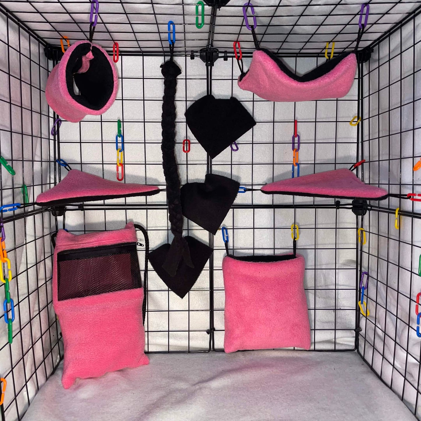 Pink and black sugar glider cage set with bonding pouch, black interior, hammocks, tunnel, blankets, and black braided rope shown in a display cage.