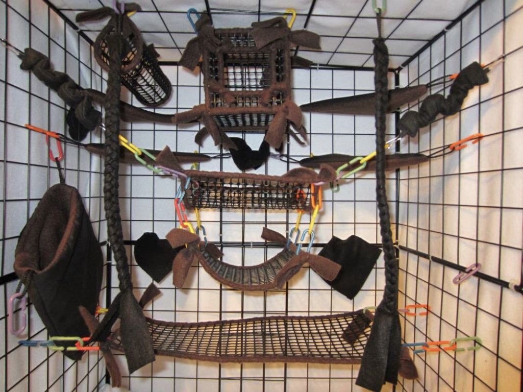 15-piece brown mesh sugar glider cage set displayed in an enclosure, featuring cube pouches, hammocks, and breathable accessories for small pet comfort.