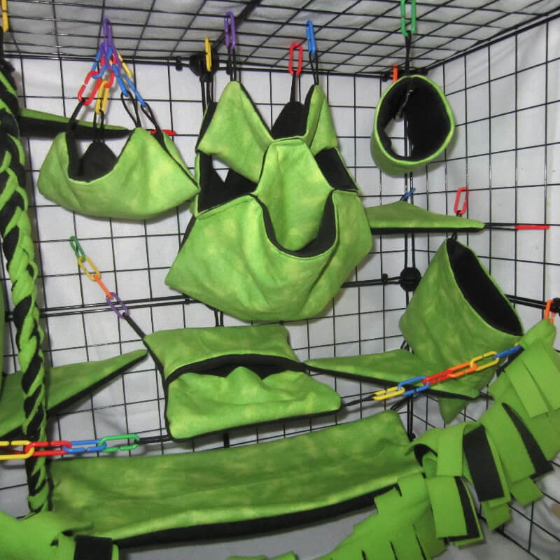 Close-up of jungle green fleece sugar glider accessories including pouches and hammocks