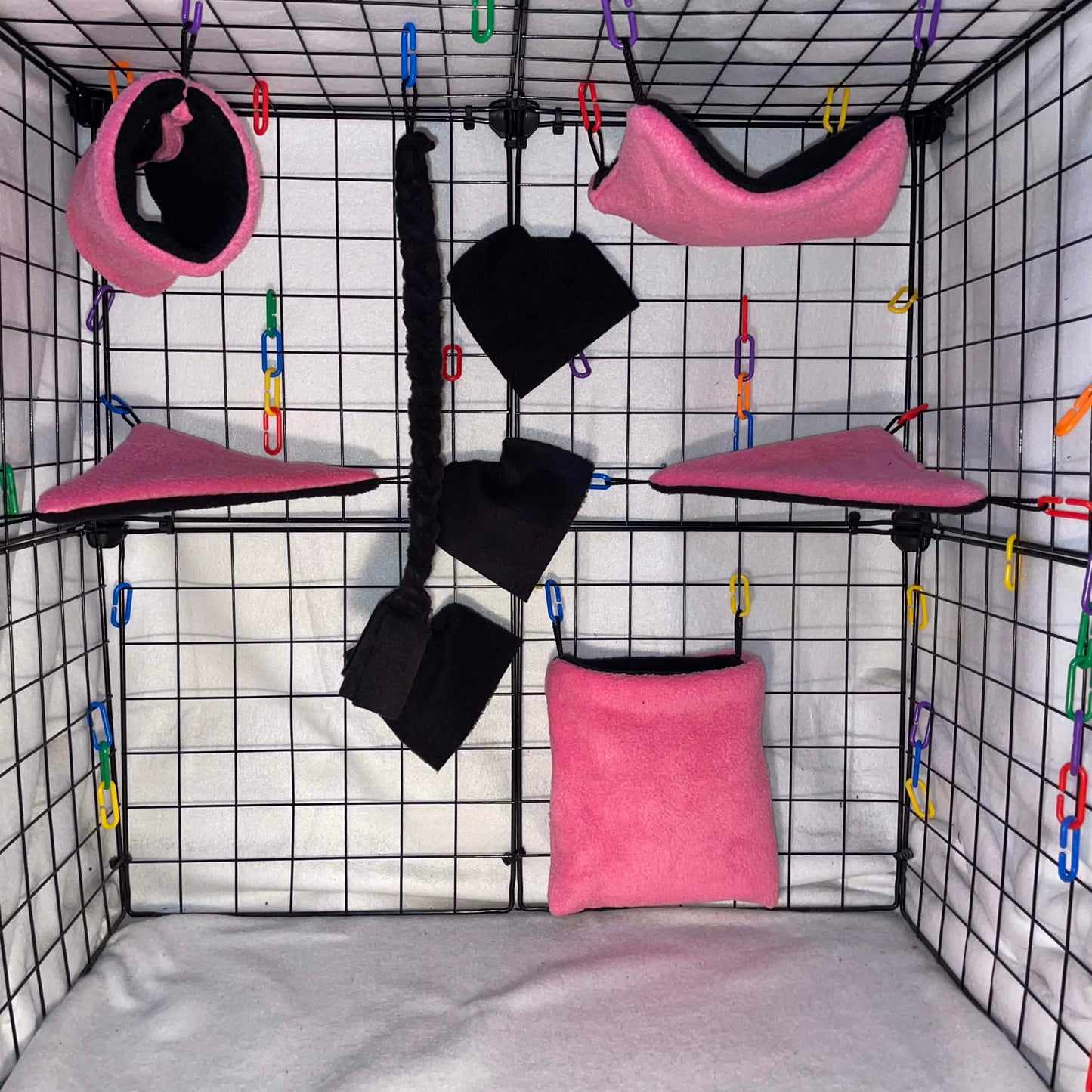 Pink and black sugar glider cage set with black interior, hammocks, tunnel, pouch, blankets, and black braided rope shown in a display cage.