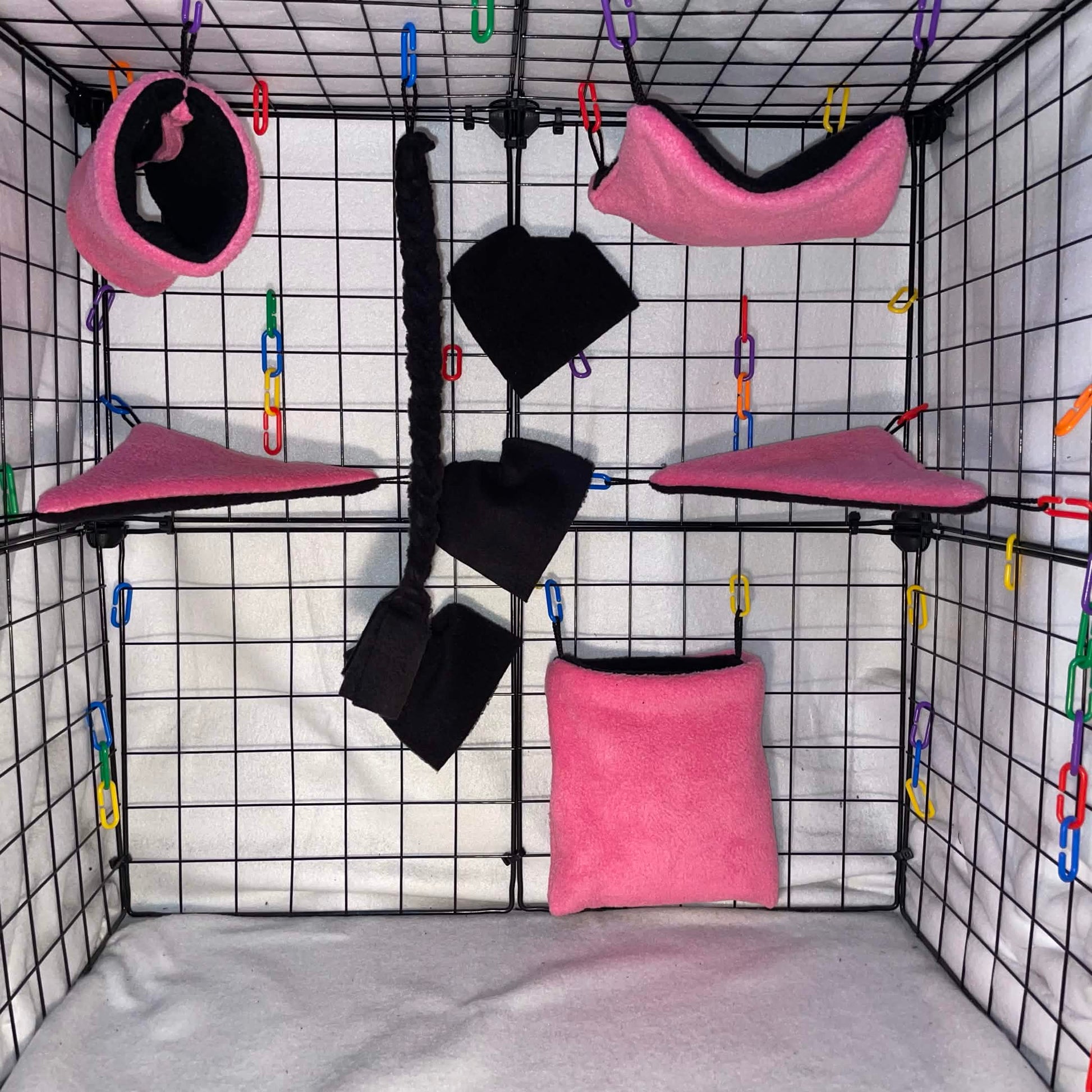 Pink and black sugar glider cage set with black interior, hammocks, tunnel, pouch, blankets, and black braided rope shown in a display cage.