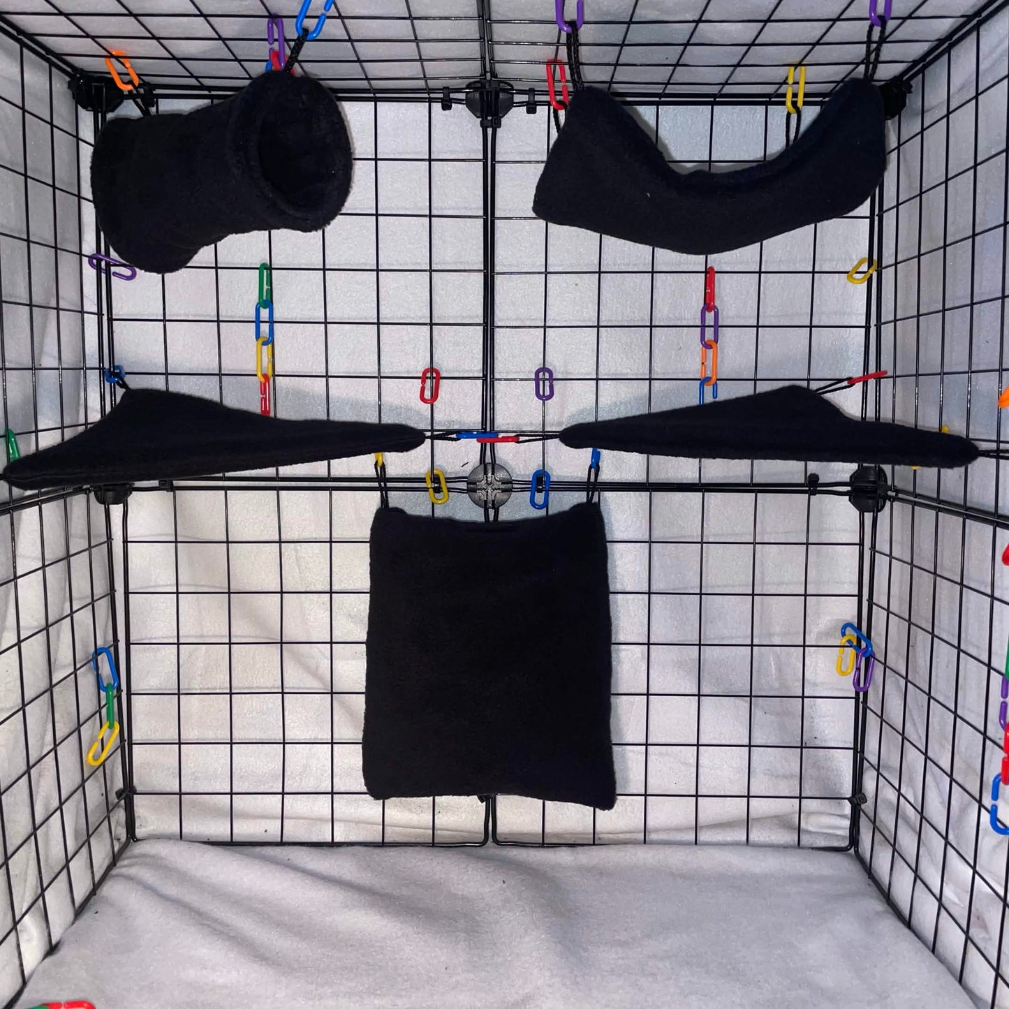 Black fleece sugar glider expansion cage set with pouch, hammock, shelves, and colorful C-links inside a wire cage.