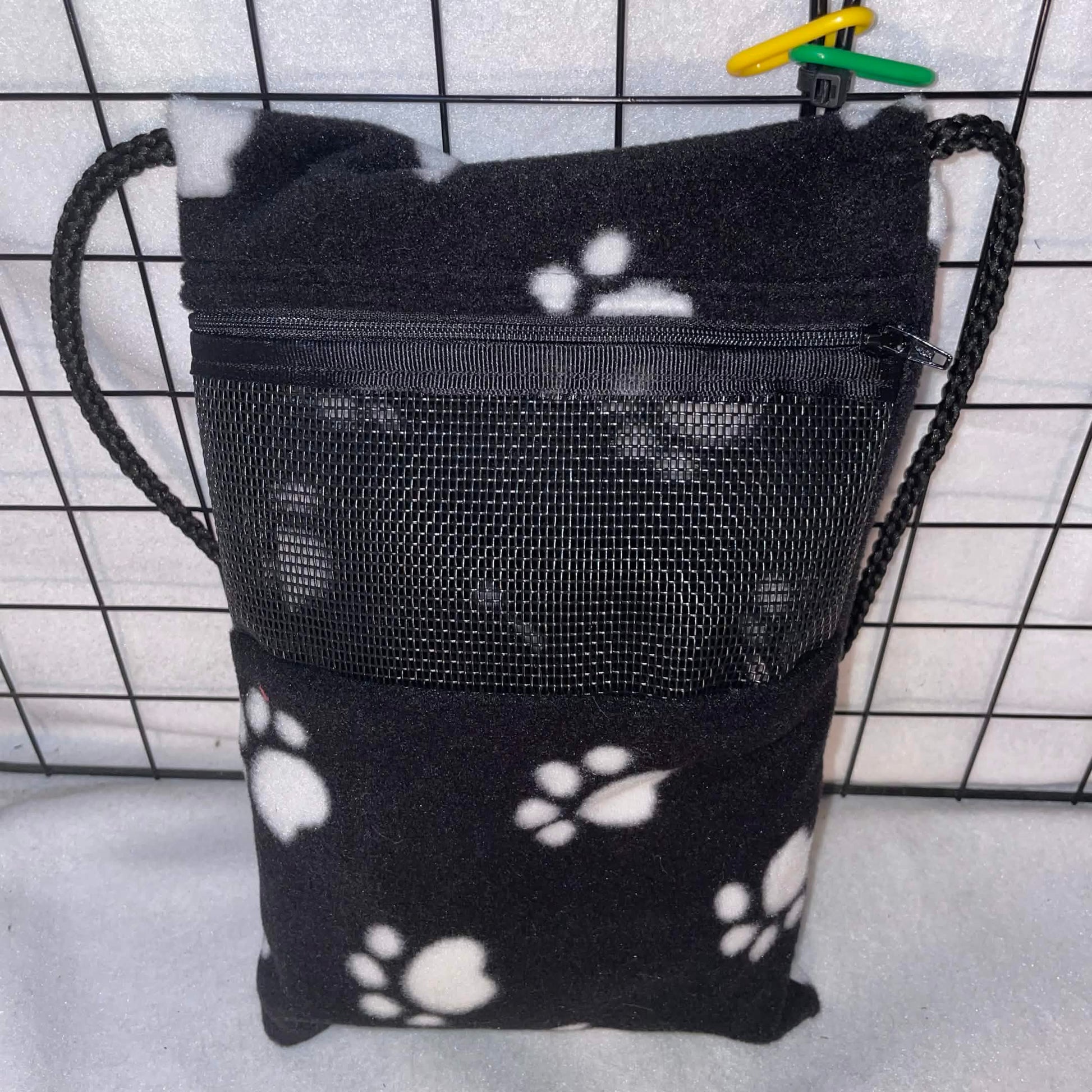 Black paw print sugar glider bonding pouch with black mesh window and shoulder strap shown inside a display cage.