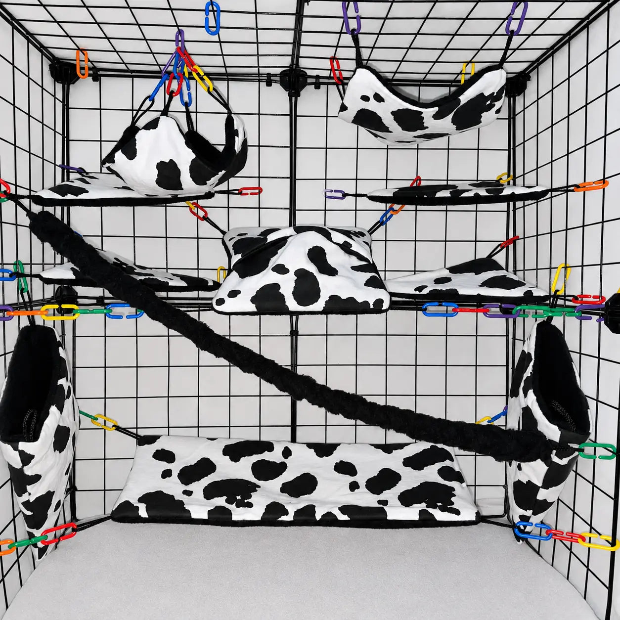 Cow print sugar glider cage set in a display cage with hammocks, pouches, bridge, black fleece vine, and black interior fleece.