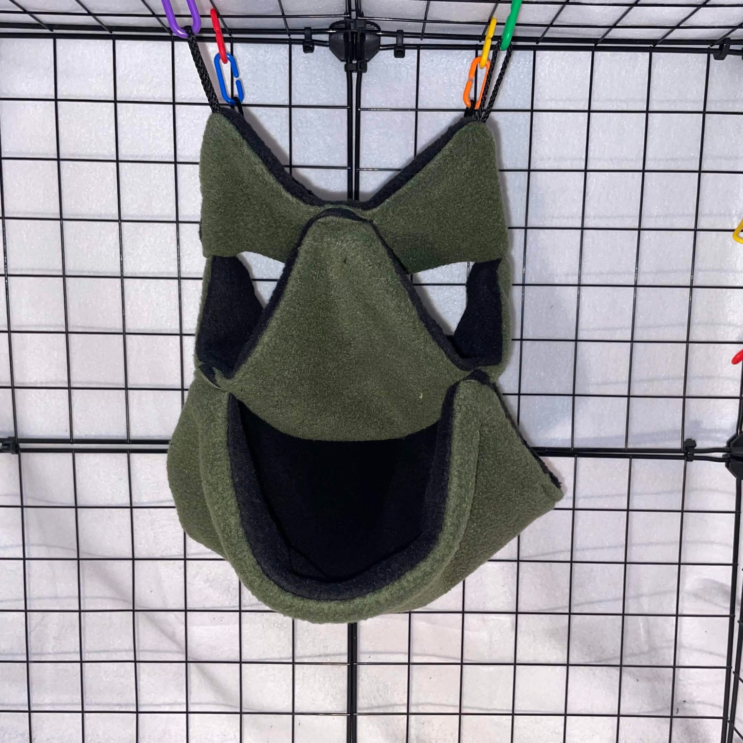 Forest green sugar glider 3-tier honeycomb hammock with black interior hanging in a wire cage.