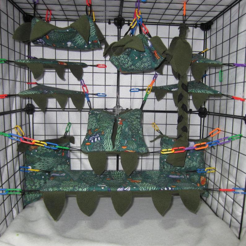 Pine Forrest print sugar glider cage set with green fleece hammocks, pouches, shelves, braided rope, and leaf accents installed in a wire cage.