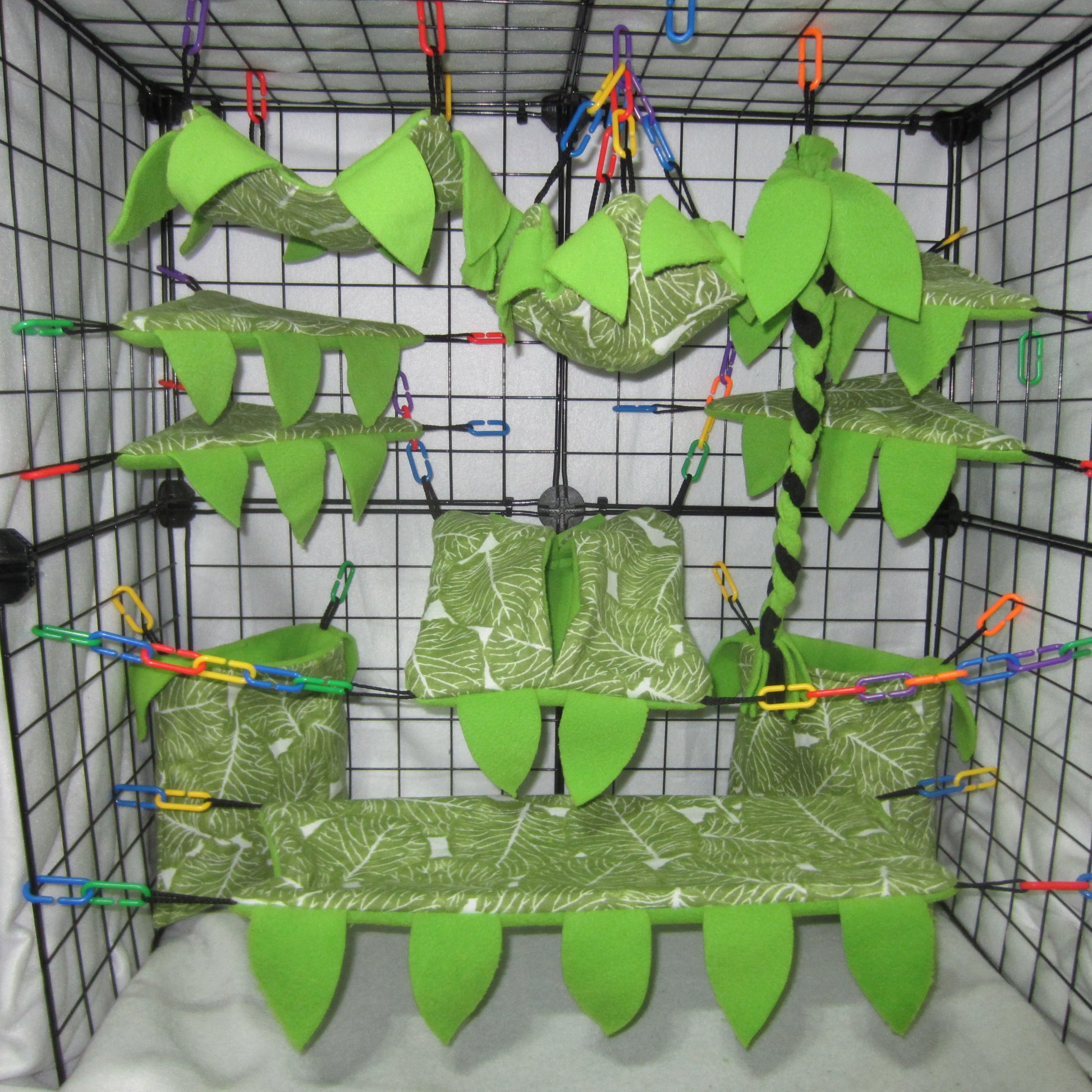Green leaf print sugar glider cage set with fleece hammocks, pouches, shelves, braided rope, and leaf accents installed in a wire cage.