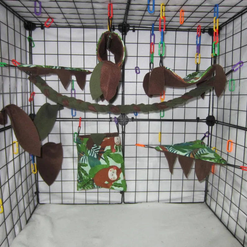 Sloth jungle print sugar glider cage set with brown and green fleece hammocks, pouches, shelves, braided rope, and leaf accents installed in a wire cage.