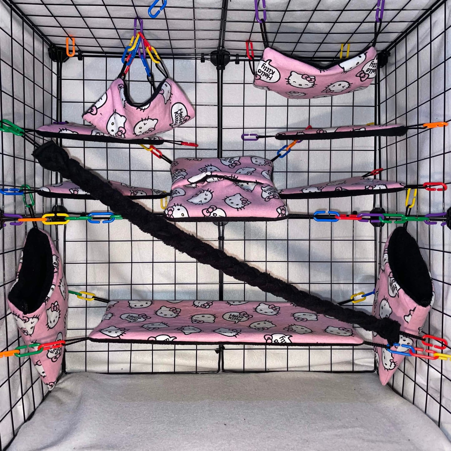 Pink kitty print sugar glider cage set in a display cage with hammocks, pouches, bridge, black fleece vine, and black interior fleece.