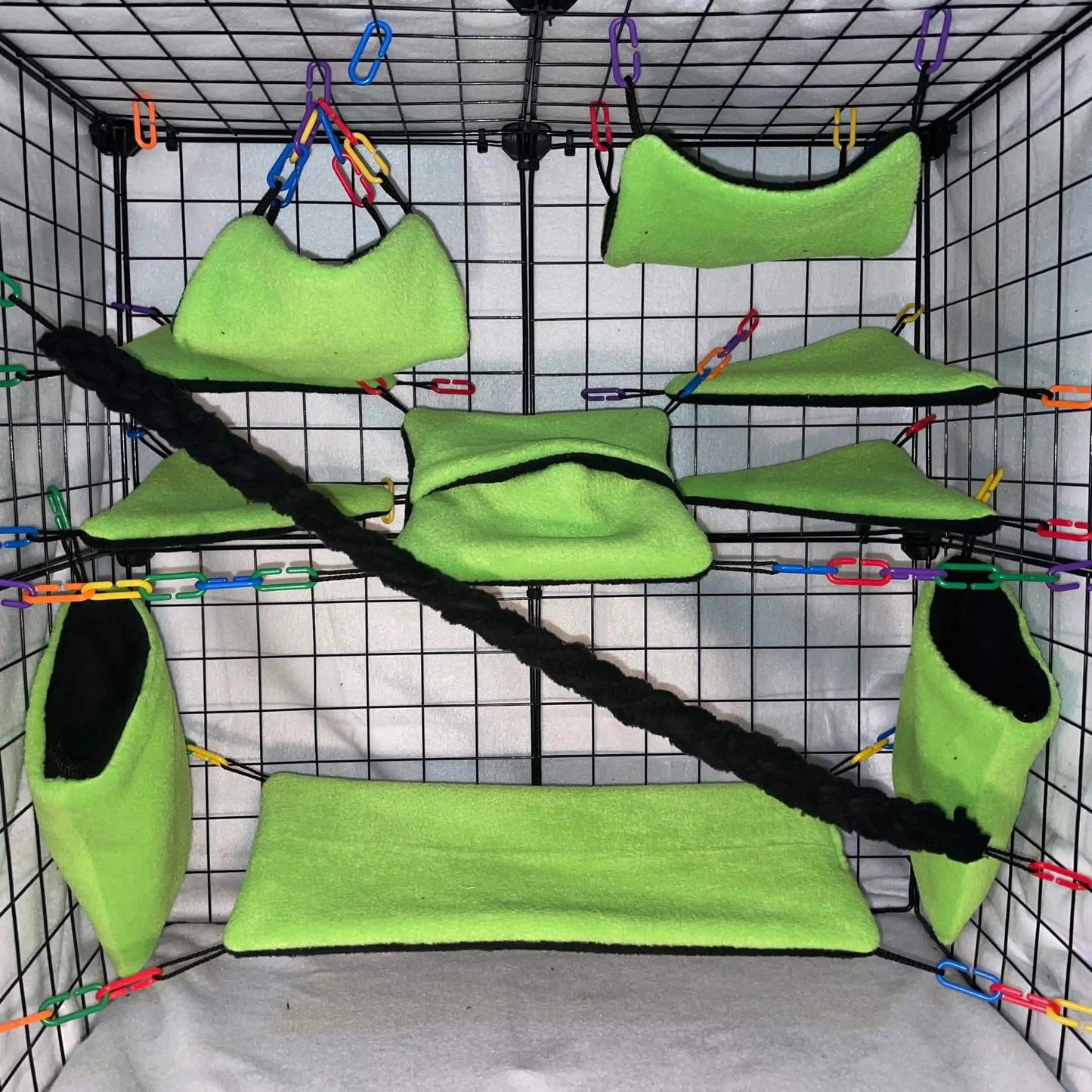 Green small animal cage set with hammocks and pouches on a grid display background