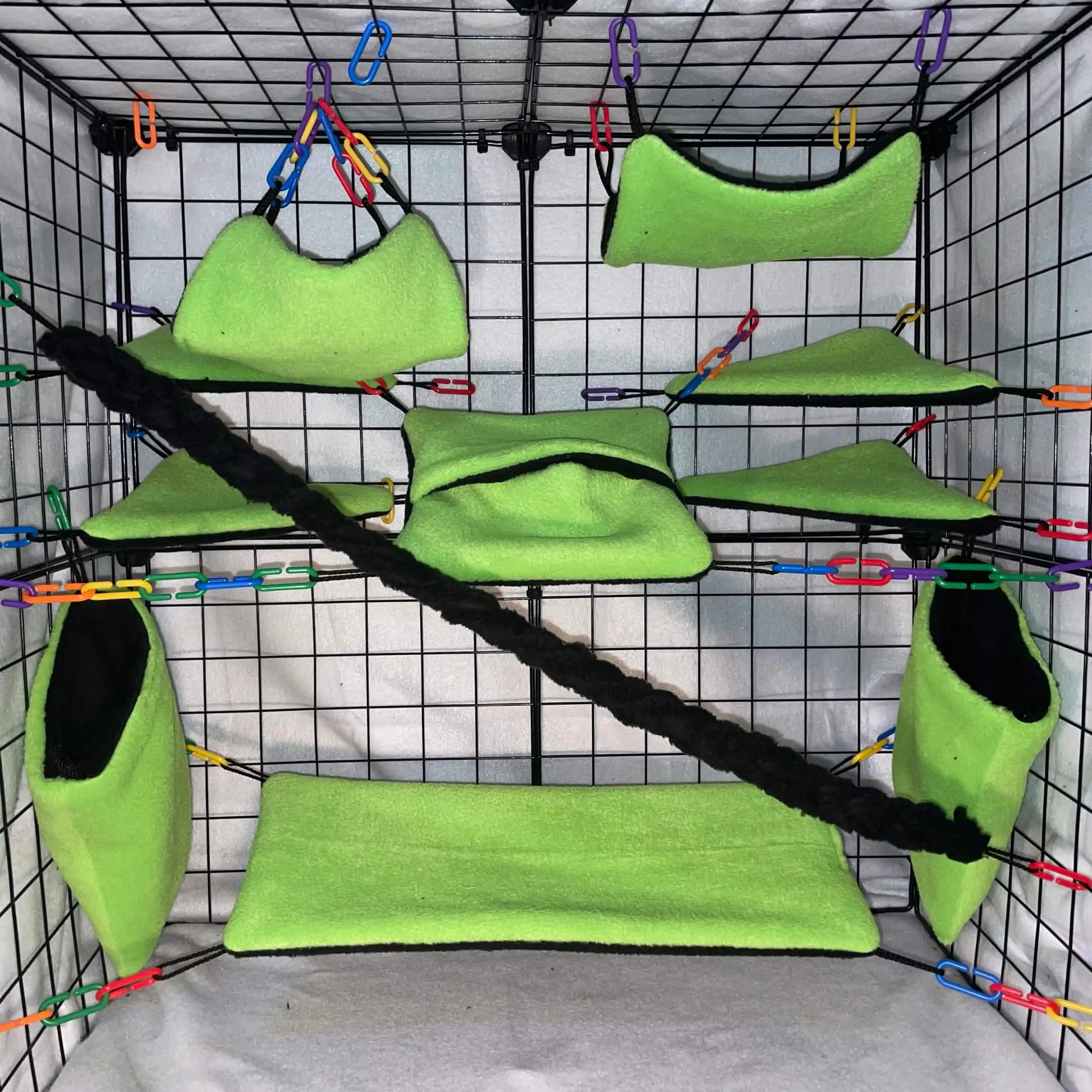 Green small animal cage set with hammocks and pouches on a grid display background