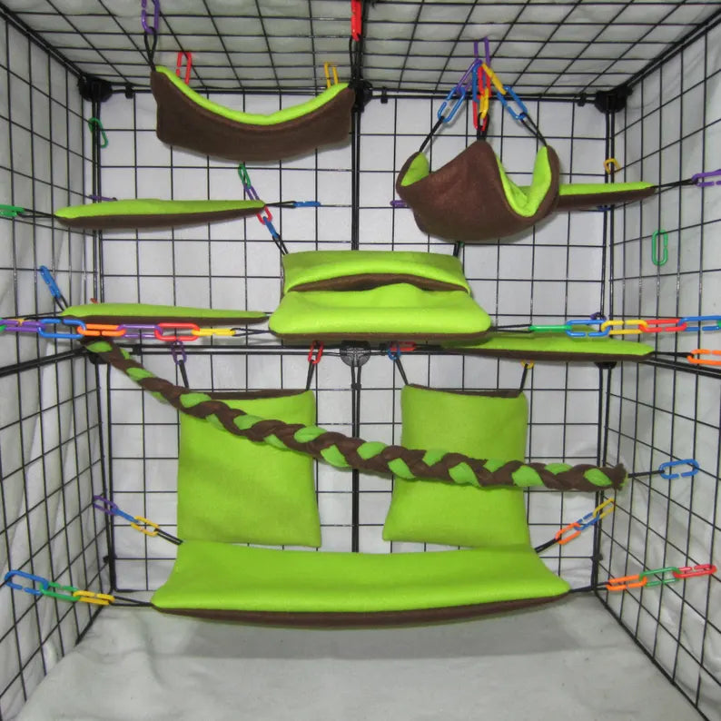 Green and brown sugar glider cage set with fleece hammocks, pouches, shelves, and braided rope installed in a wire cage.