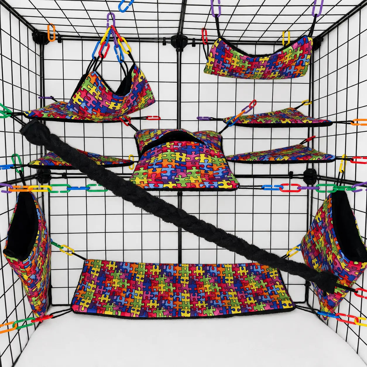 Colorful rainbow puzzle print sugar glider cage set with black fleece interior of pouches, hammocks, shelves, bridge, and braided rope inside a display cage.