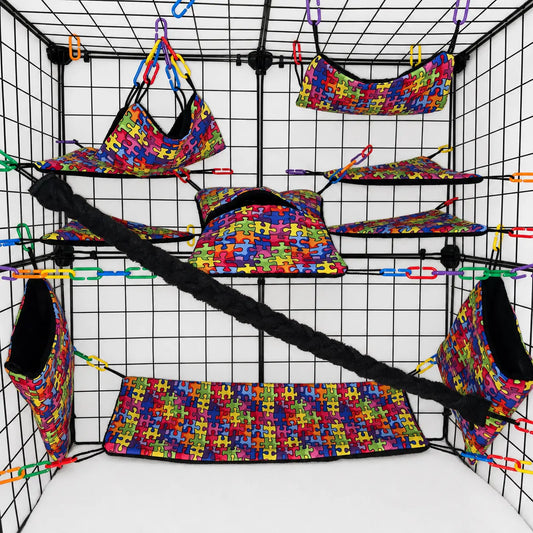 Colorful rainbow puzzle print sugar glider cage set with black fleece interior of pouches, hammocks, shelves, bridge, and braided rope inside a display cage.