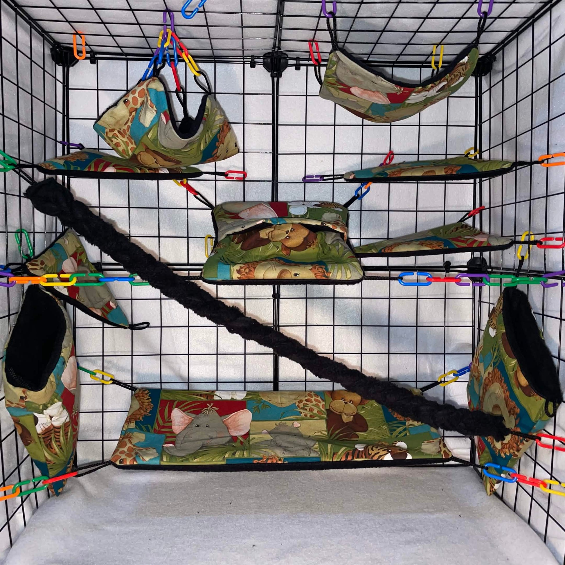 Safari animal print sugar glider cage set with black interior of pouches, hammocks, shelves, bridge, and braided rope inside a display cage.