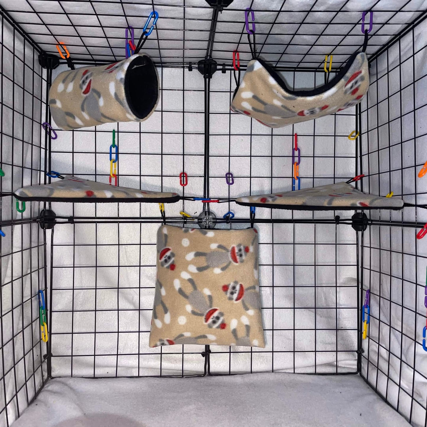 Sock monkey print sugar glider fleece expansion set with pouch, hammock, tunnel, and corner shelves installed in a wire cage.