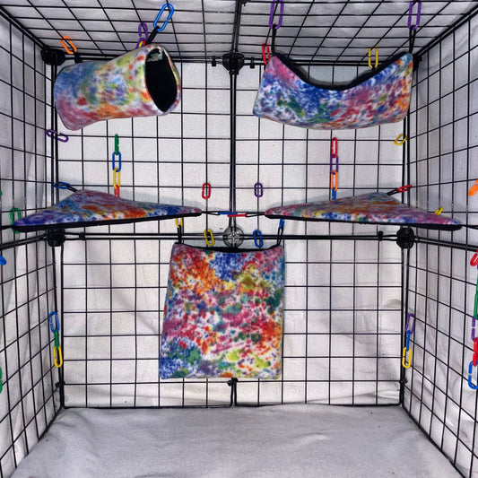 Splatter Paint Rainbow tie-dye sugar glider fleece expansion set with pouch, hammock, tunnel, and corner shelves installed in a wire display cage.