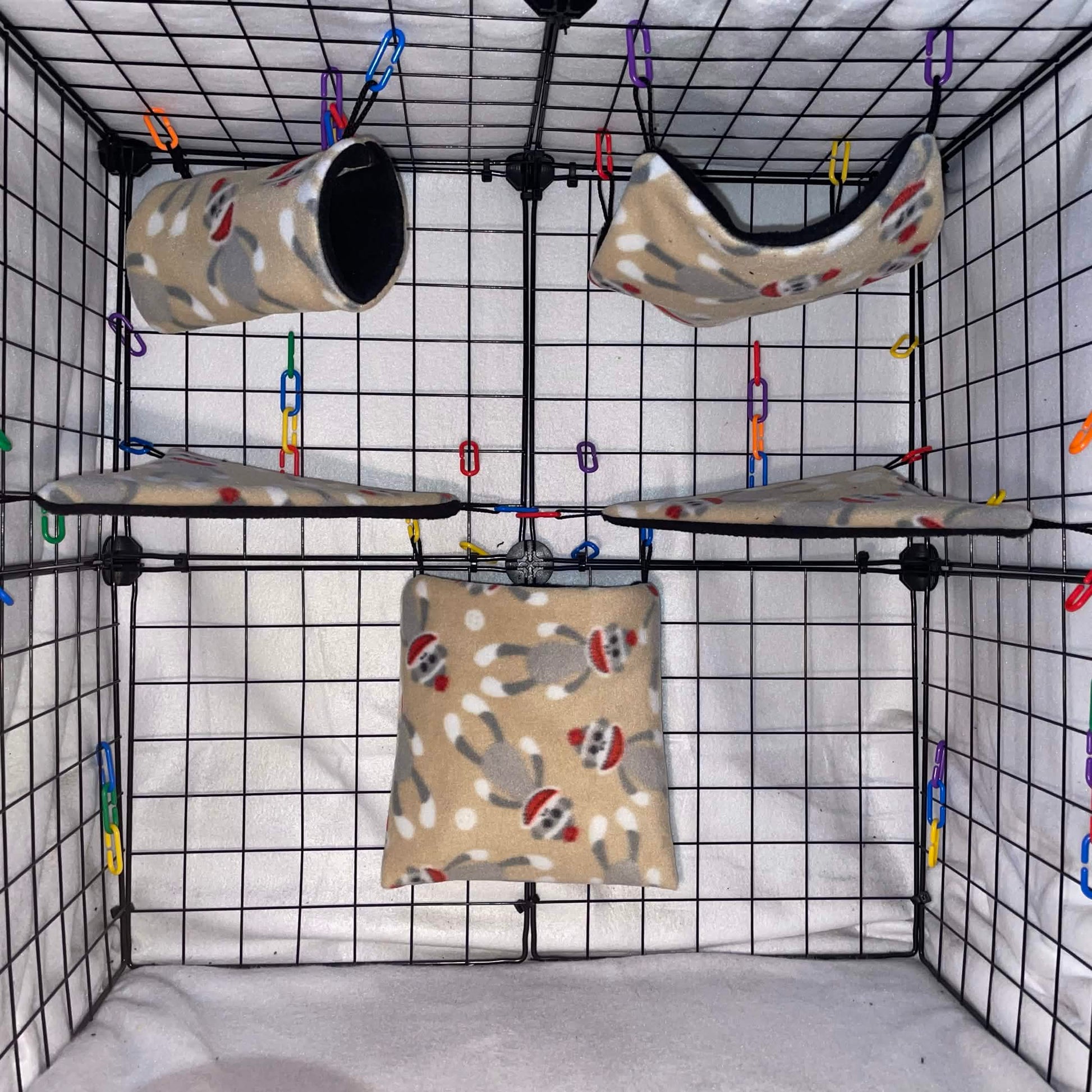 Tan sock monkey print sugar glider cage set with black interior, hammocks, tunnel, pouch, and corner shelves shown in a display cage.