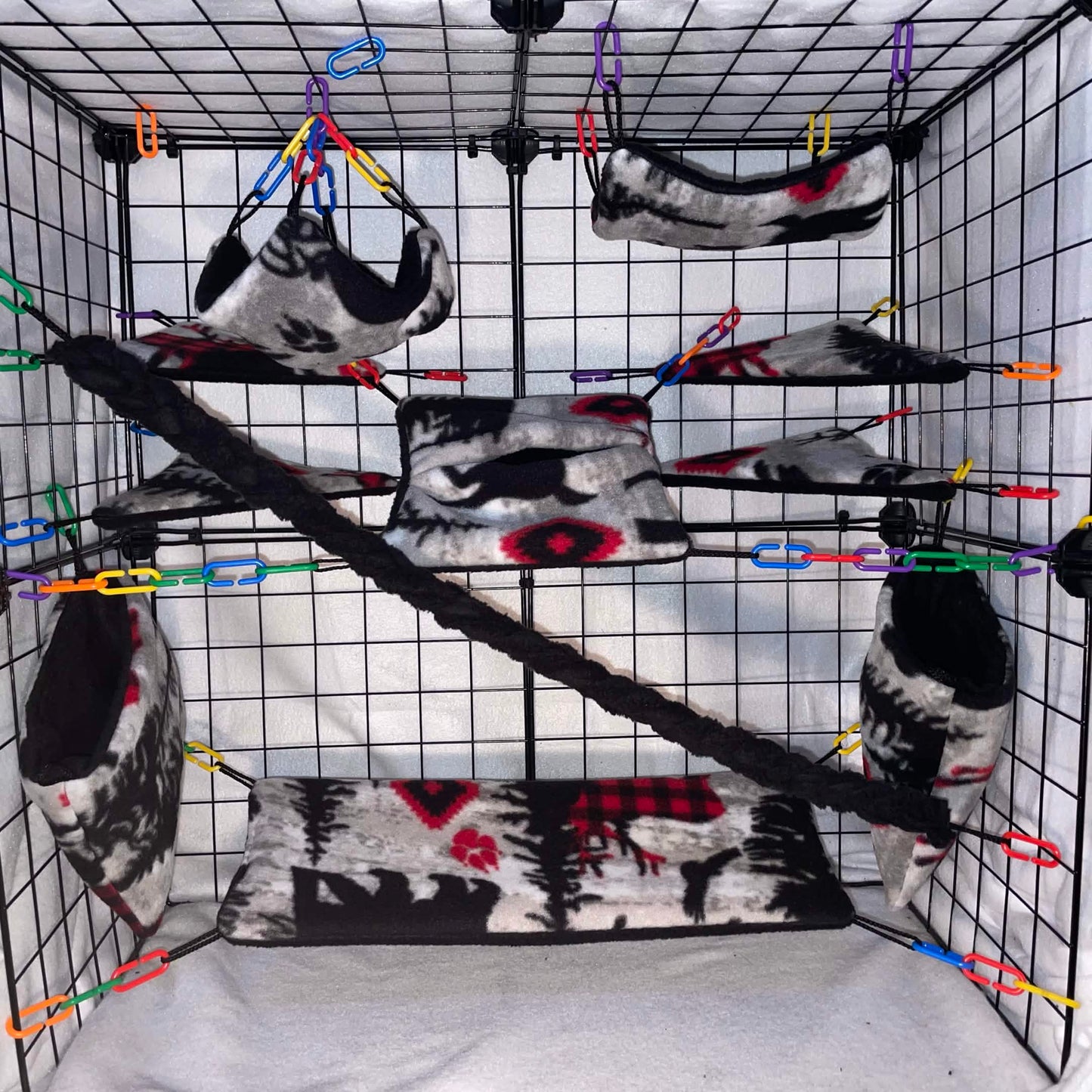 Woodsman print sugar glider cage set with fleece hammocks, pouches, shelves, and black braided rope installed in a wire cage.