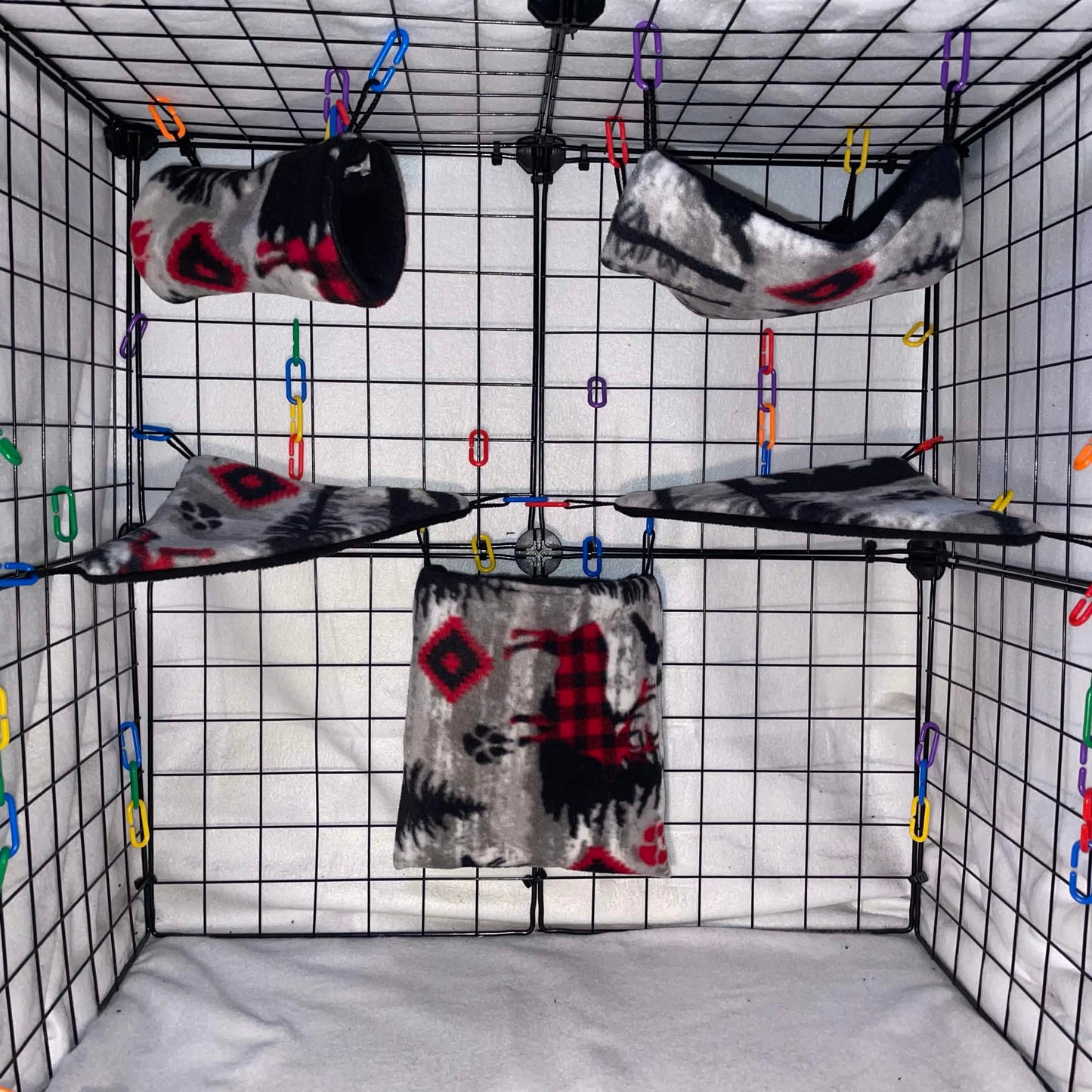 Woodsman print sugar glider fleece expansion set with pouch, hammock, tunnel, and corner shelves installed in a wire cage.