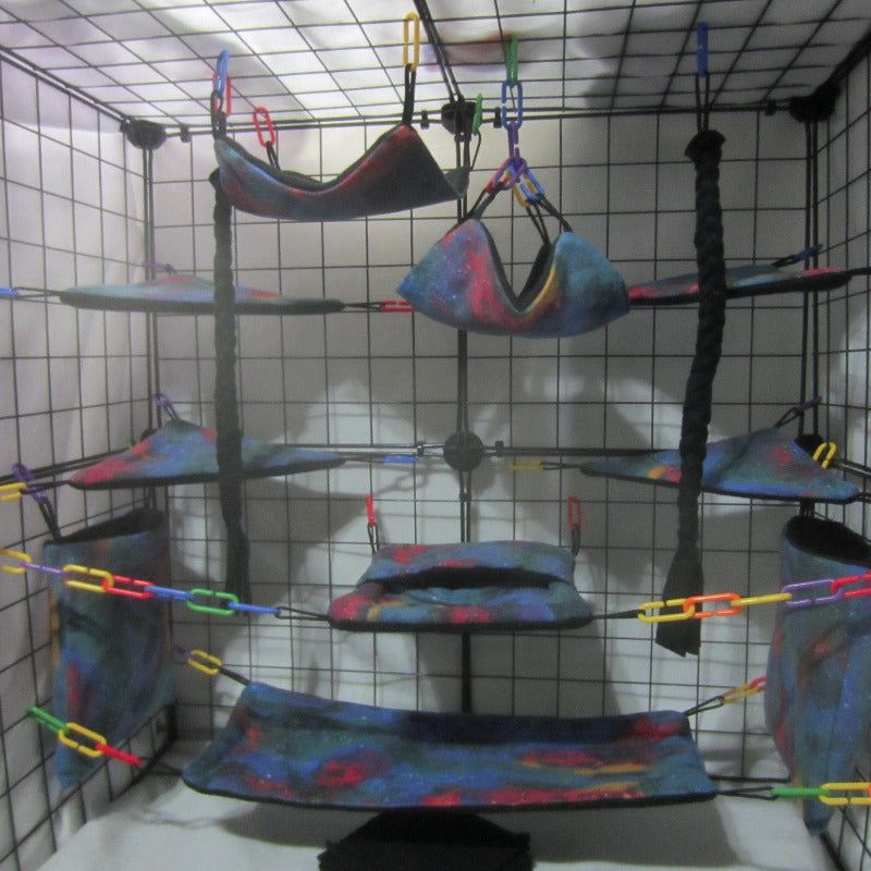 17-piece sugar glider cage set featuring blue galaxy tie dye fabric, including hammocks, pouches, and accessories arranged inside a display cage for small pet comfort and enrichment.