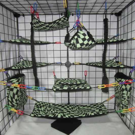 17-piece sugar glider cage set featuring green checkered flag fleece and fabric, including hammocks, pouches, and accessories arranged inside a metal cage for small pet comfort and enrichment.