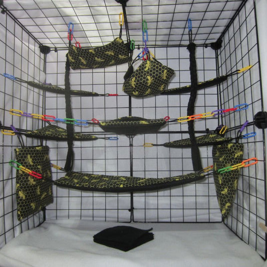 17-piece sugar glider cage set featuring honey and bee-themed fleece and fabric, including hammocks, pouches, corner shelves, braided ropes, fleece blankets, and assorted C-links arranged inside a metal cage for small pet comfort and enrichment.