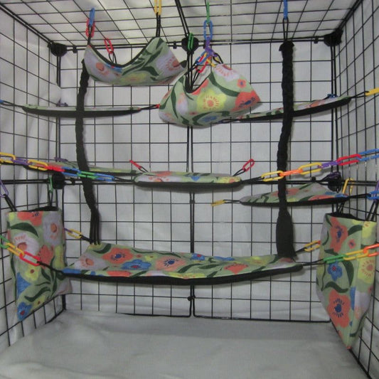 17-piece sugar glider cage set featuring jungle flowers fabric, including hammocks, pouches, and accessories arranged inside a metal cage for small pet comfort and enrichment