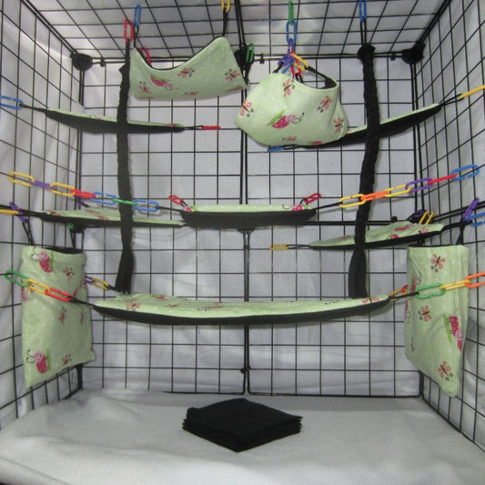 17-piece sugar glider cage set in lovely ladybug print, featuring fleece hammocks, pouches, and accessories arranged inside a display cage for small pet comfort and enrichment.