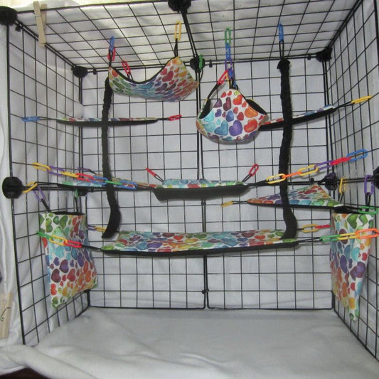 17-piece sugar glider cage set featuring multi-color hearts fabric, including hammocks, pouches, and accessories arranged inside a display cage for small pet comfort and enrichment.